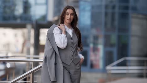 fashionable young woman in a business suit with a jacket in her hands posing stylishly