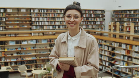 portrait of young woman with book in library