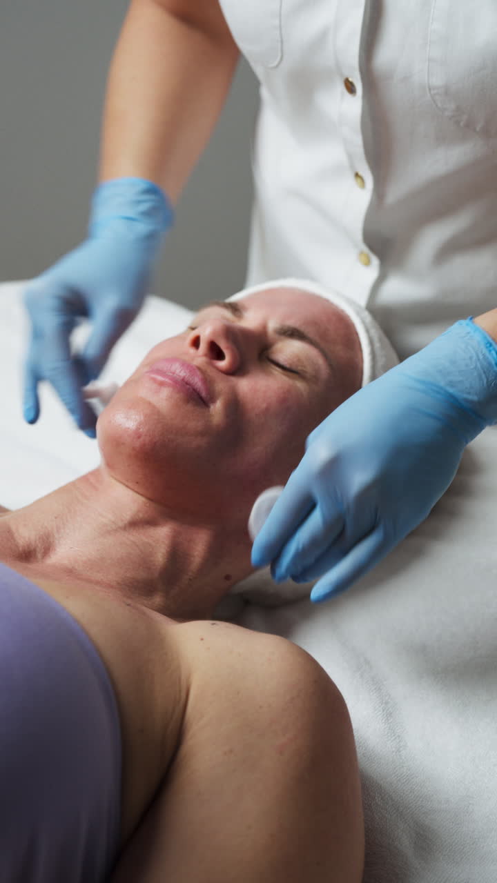 An Esthetician Gently Wiping the Client's Face and Neck With Cotton Pads - Close Up