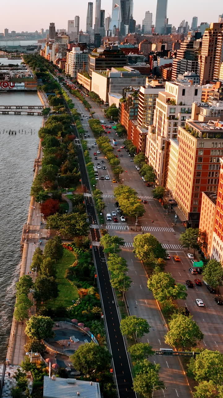 Flight above the waterfront of Hudson River. Beautiful green park and highway separating water from buildings. Aerial perspective. Vertical video