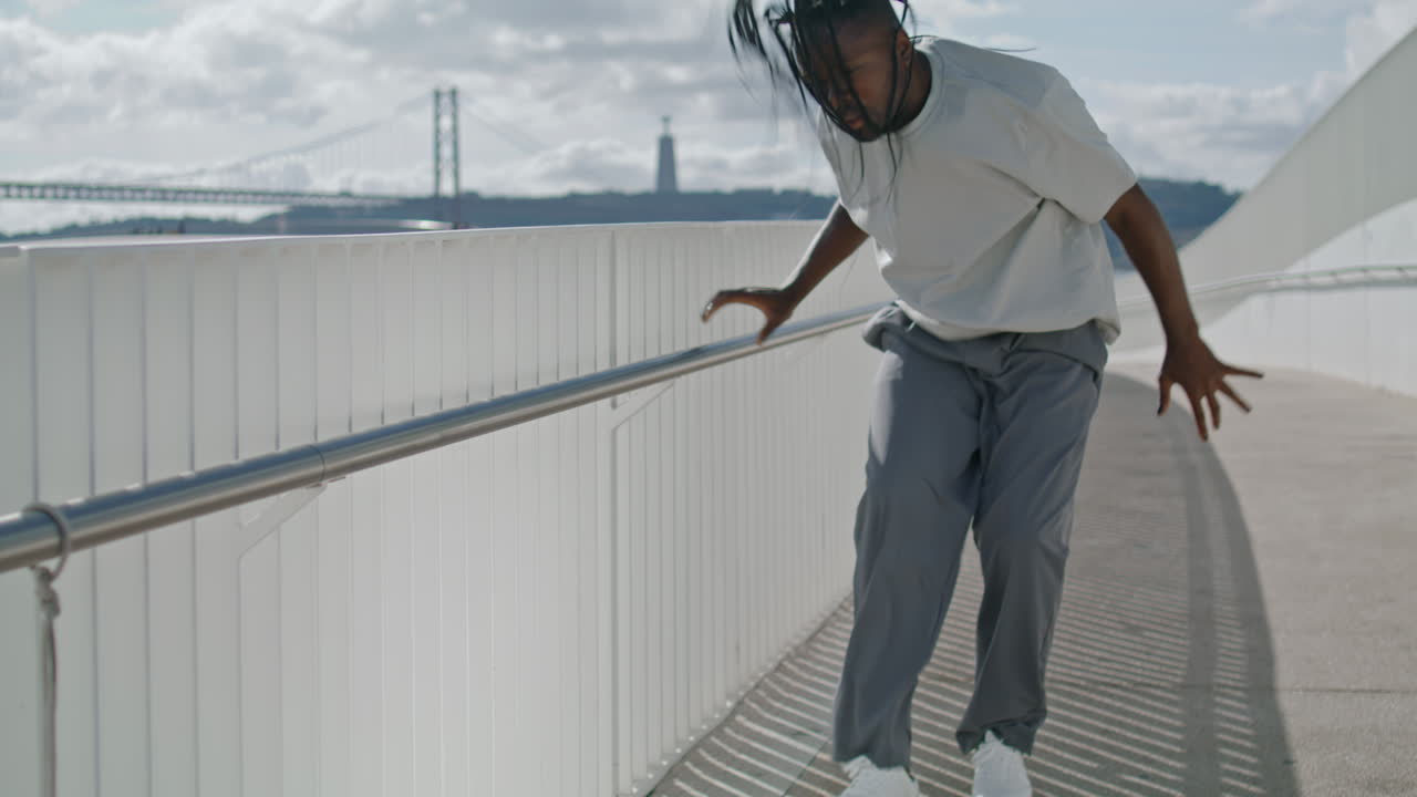 Charismatische danser kijkt in camera met zee op achtergrond. Man met dreadlocks choreografie