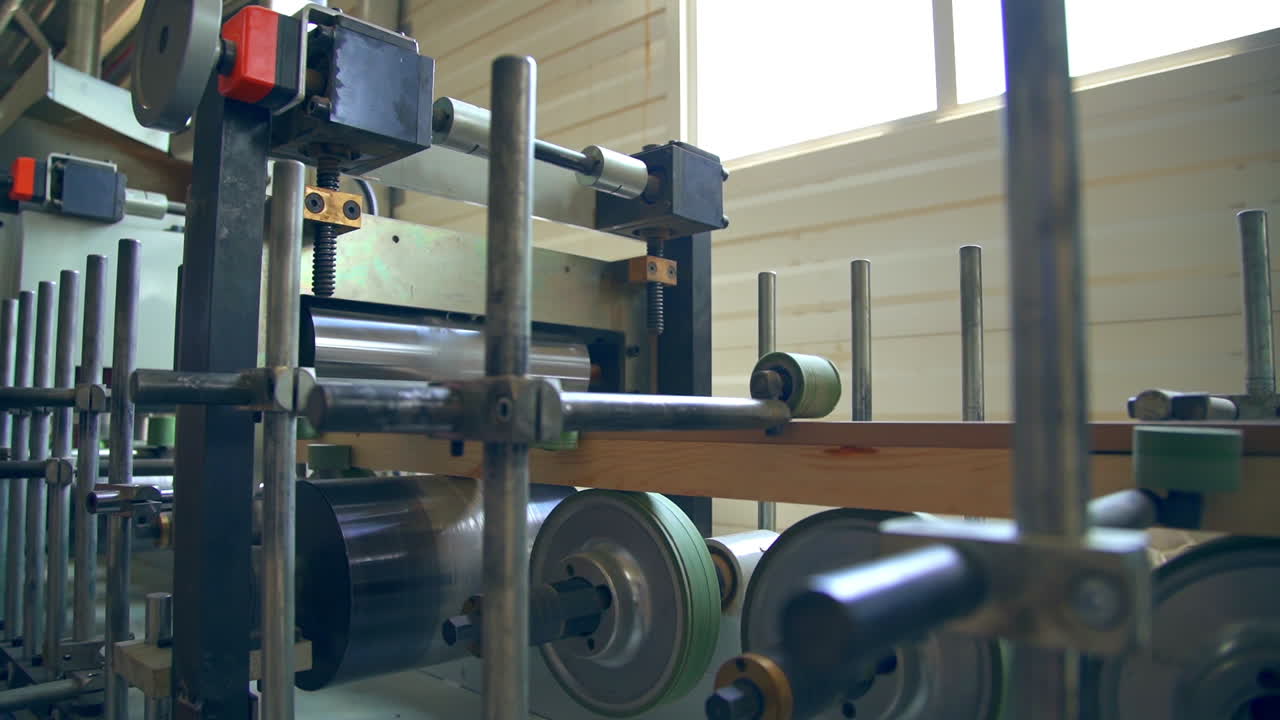 Equipment with multiple rollers of diverse width. Shafts rotate and move the timber bar further. Door manufacturing company.