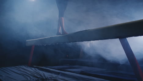 legs professional girl gymnasts jump in slow motion in the smoke on the balance beam. women's artistic gymnastics