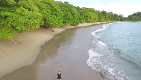 Junge-Kaukasische-Touristin-Joggt-über-Tropischen-Strand-Im-Nationalpark-Marino-Ballena,-Costa-Rica