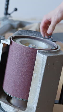 hands taking off sanding belt on floor sander machine. sanding belt replacement, vertical