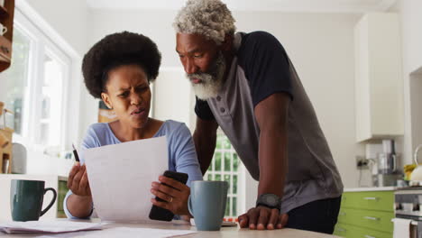 concerned african american couple sitting paying bills