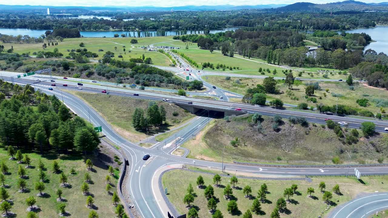 Drone aerial landscape with cars traffic travelling over bridge road highway overpass at the National Arboretum Botanical Gardens Canberra ACT Australia tourism transport Lake Burley Griffin