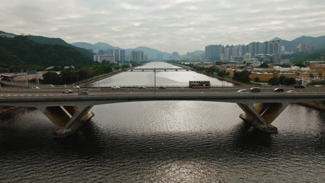 Drone-shot-of-cars-driving-on-highway-over-a-wide-waterway-bridge-in-Hong-Kong