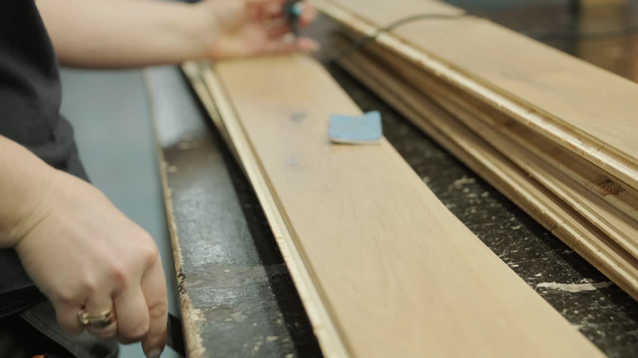 Craftsperson's Hands Working on Wooden Floorboards with Filler and Wood Burner