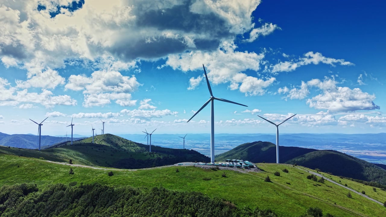 Le pale eoliche girano su una collina verde sotto un cielo blu con nuvole in una zona rurale durante le ore diurne