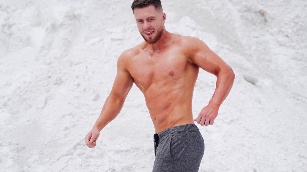 Bodybuilder uomo a torso nudo che mostra i suoi grandi muscoli forti. Allenamento all'aperto
