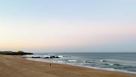 Drohnenaufnahme-Von-Guincho-Beach-Bei-Sonnenaufgang-In-Cascais,-Mit-Blick-Auf-Bar-Do-Guincho,-Muchaxo