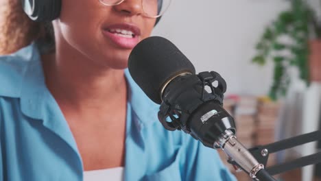 joven afroamericana lee texto en el micrófono se sienta en el estudio de grabación