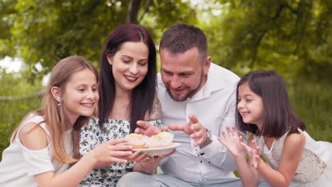 familia feliz disfrutando de pasteles en un picnic en el parque