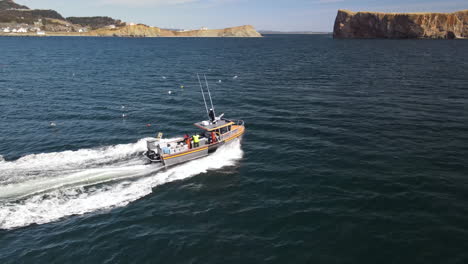 Lobster-fishing-boat-lifting-cages-in-the-morning-in-front-of-Rocher-Percé-in-Percé,-Qc