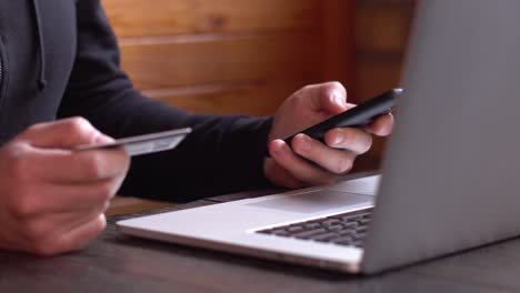 businessman in a black hoodie making online payment with credit card and smartphone, online shopping