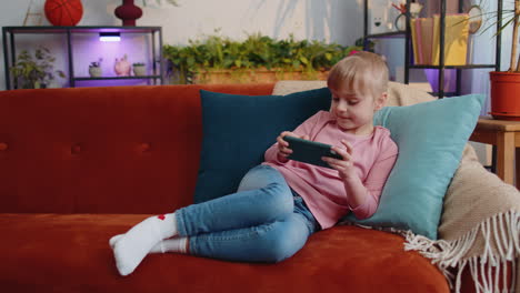 Worried-teen-child-girl-kid-enthusiastically-playing-racing-video-online-games-on-smartphone-at-home