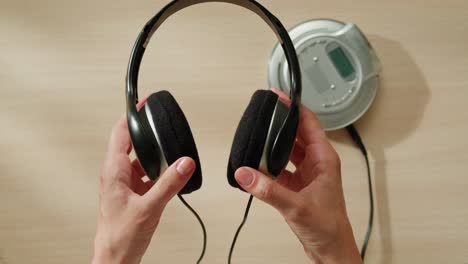 manos sosteniendo un reproductor de cd portátil y auriculares