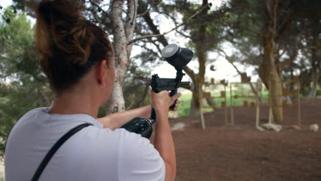 a woman shooing paintballs with a paint ball gun at a paintballing target range