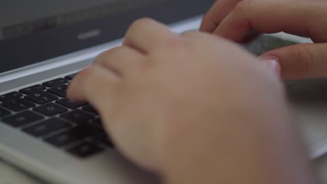 A-young-man-is-typing-on-the-silver-laptop's-keyword-outside