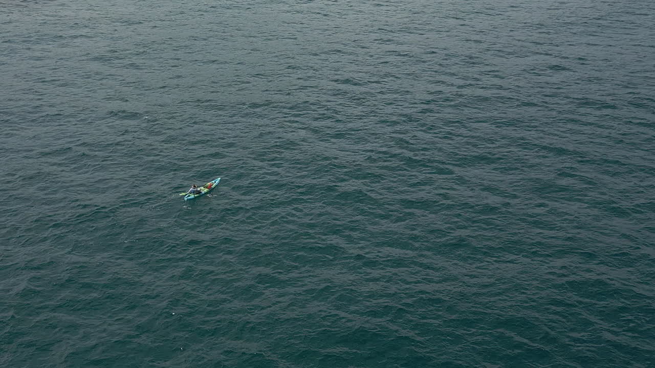 vista aérea de una persona remando kayak inflable en el agua del océano debajo