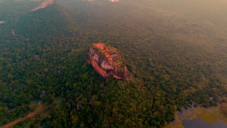 breathtaking aerial drone footage flying over sigiriya rock fortress at sunrise in sri lanka.