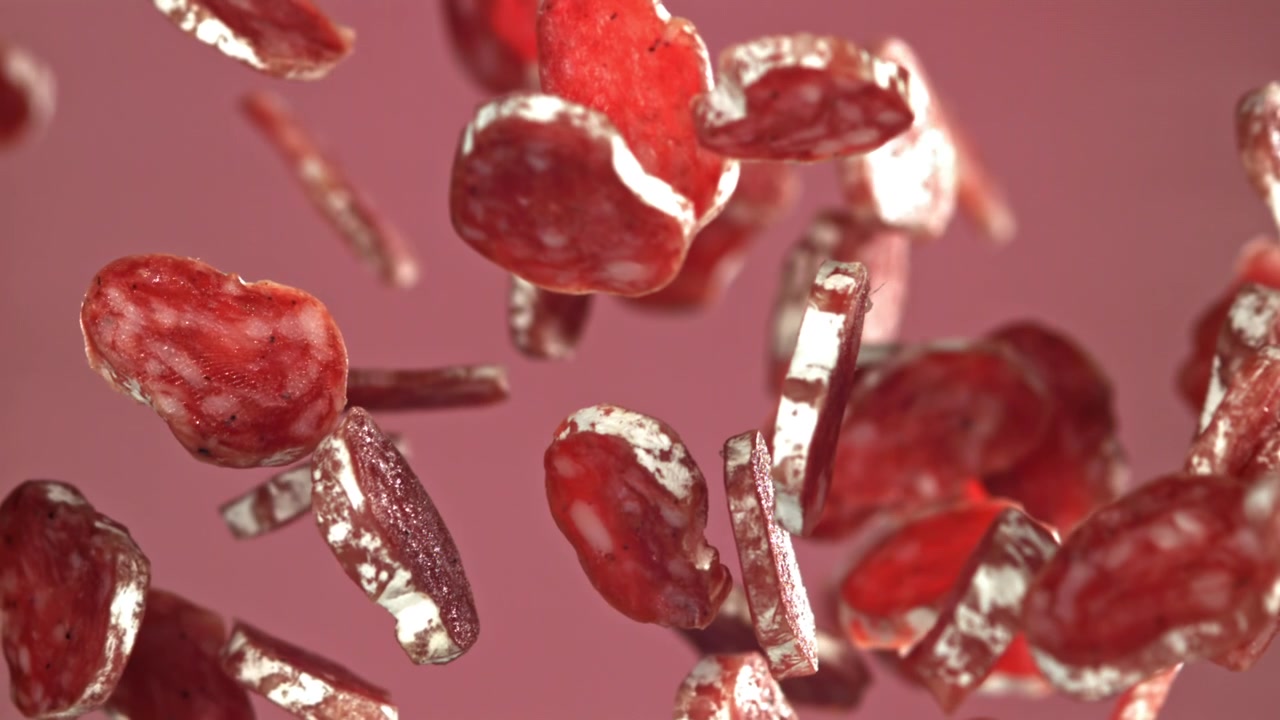 Salami Slices Falling in Slow Motion Against a Pink Background