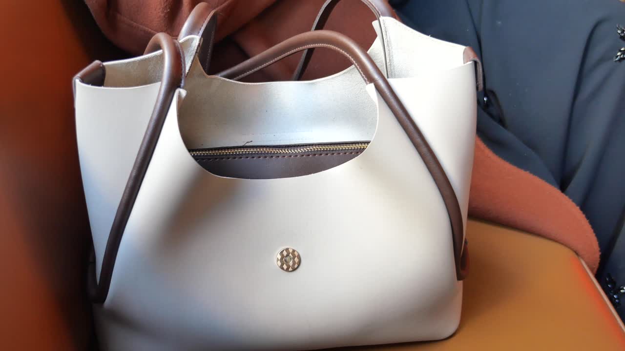 mujer sentada con un bolso blanco