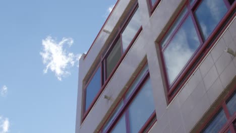 footage of a building with sky-reflexion in the windows.