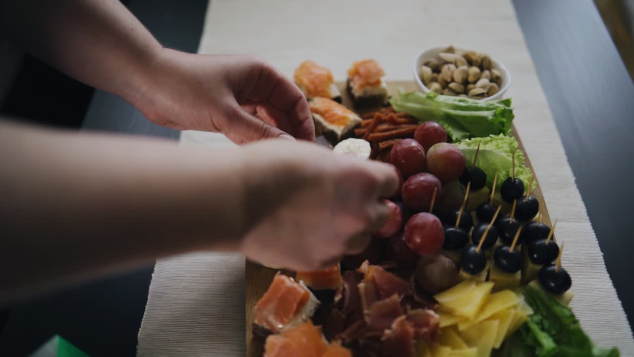 una mujer decora una bandeja con bocadillos en la mesa con pedazos de chocolate. comida muy sabrosa en la mesa