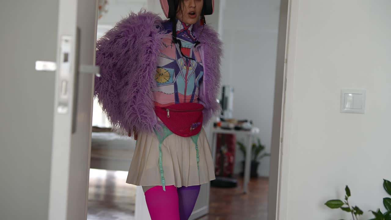 Giovane donna con un outfit eccentrico e colorato e un casco rosa in piedi sulla soglia