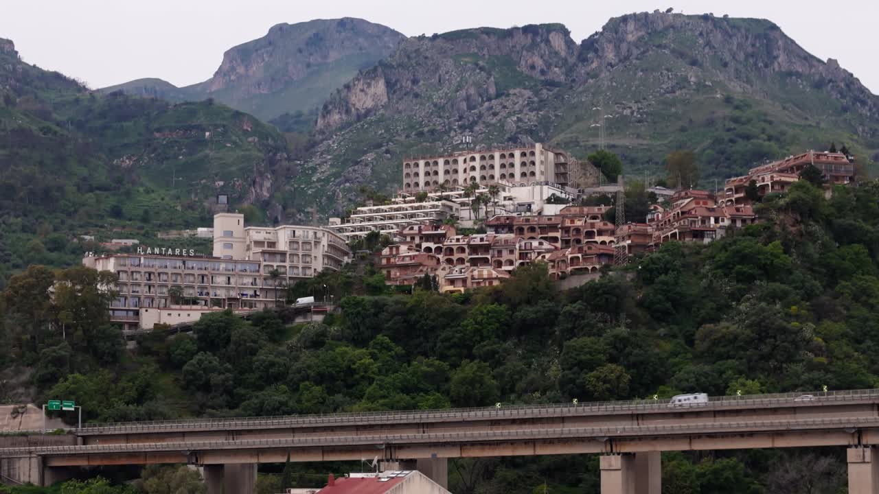 Cinematic aerial drone tilt-down shot revealing a hidden city on the mountain, surrounded by nature in Letojanni, near Taormina, Sicily, Italy (Sicilia, Italia)