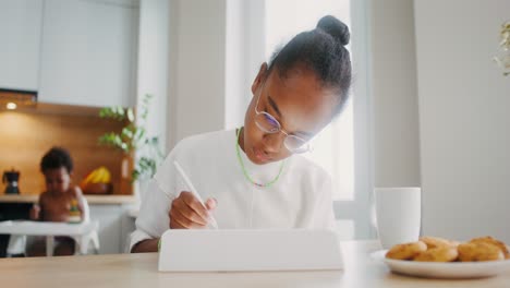 girl studying on a tablet in a kitchen