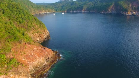 flying by an island shoreline to reveal two yachts anchored at carrizal anchorage near manzanillo, mexico in a beautiful protected bay at sunset