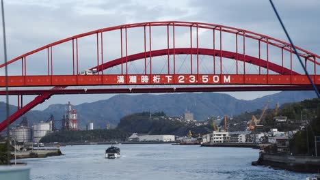 view from a ferry under passing a red traffic bridge in japanese sea