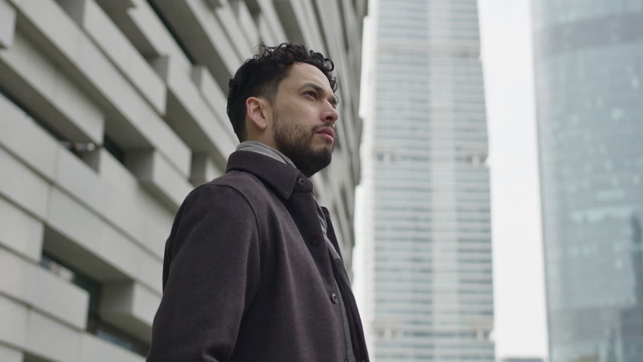 joven empresario exitoso, vestido con ropa de otoño, se encuentra solo en el distrito comercial del centro, pensando, contemplando la vida