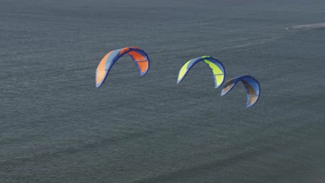 three colorful power kites flying in the air above a seascape