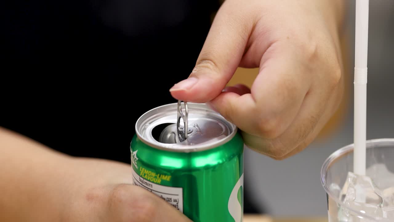 Close-up of hand opening aluminum lemon lime soda can, bright lighting, steady camera, indoor setting