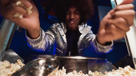 cheerful black man eating popcorn from machine