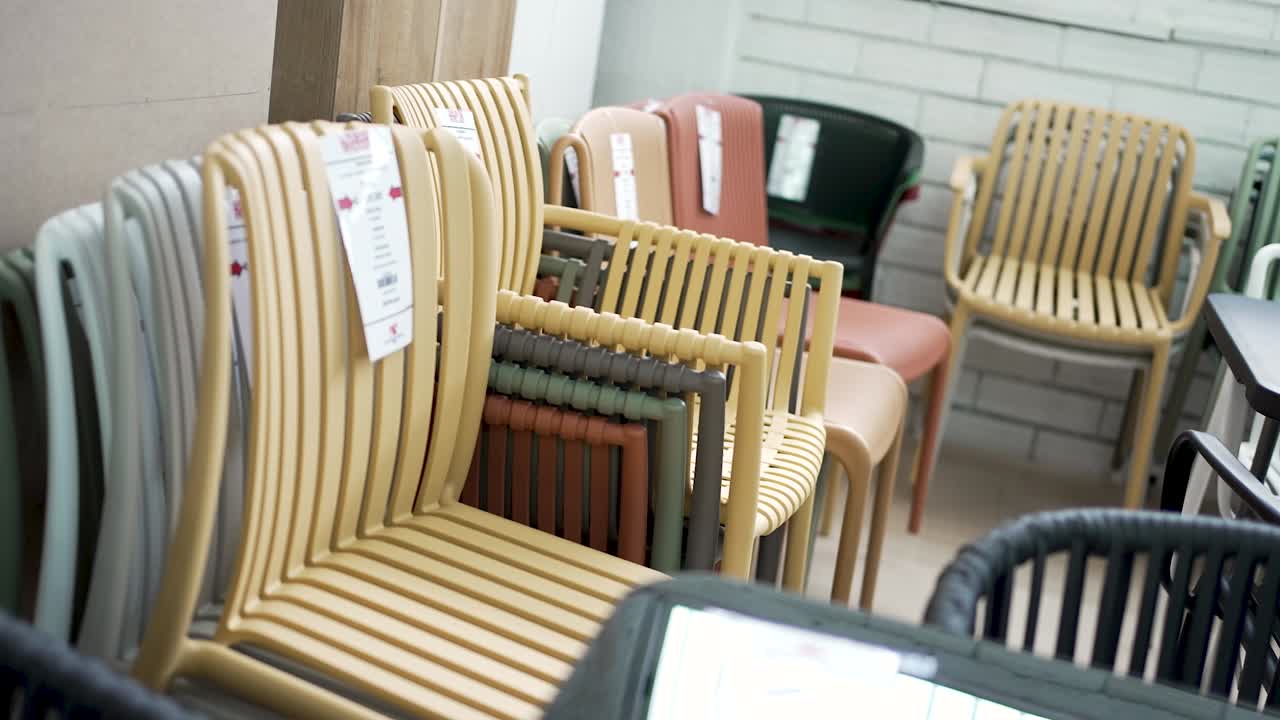 Various colorful outdoor chairs are neatly arranged in a contemporary furniture store. Each chair exhibits a unique design, ready for shoppers looking to enhance their outdoor space