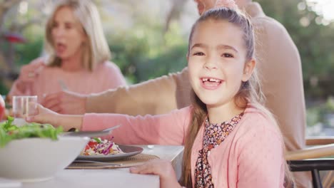 Vídeo-De-Una-Feliz-Hija-Caucásica-Girándose-Y-Riéndose-En-La-Mesa-Familiar-Al-Aire-Libre