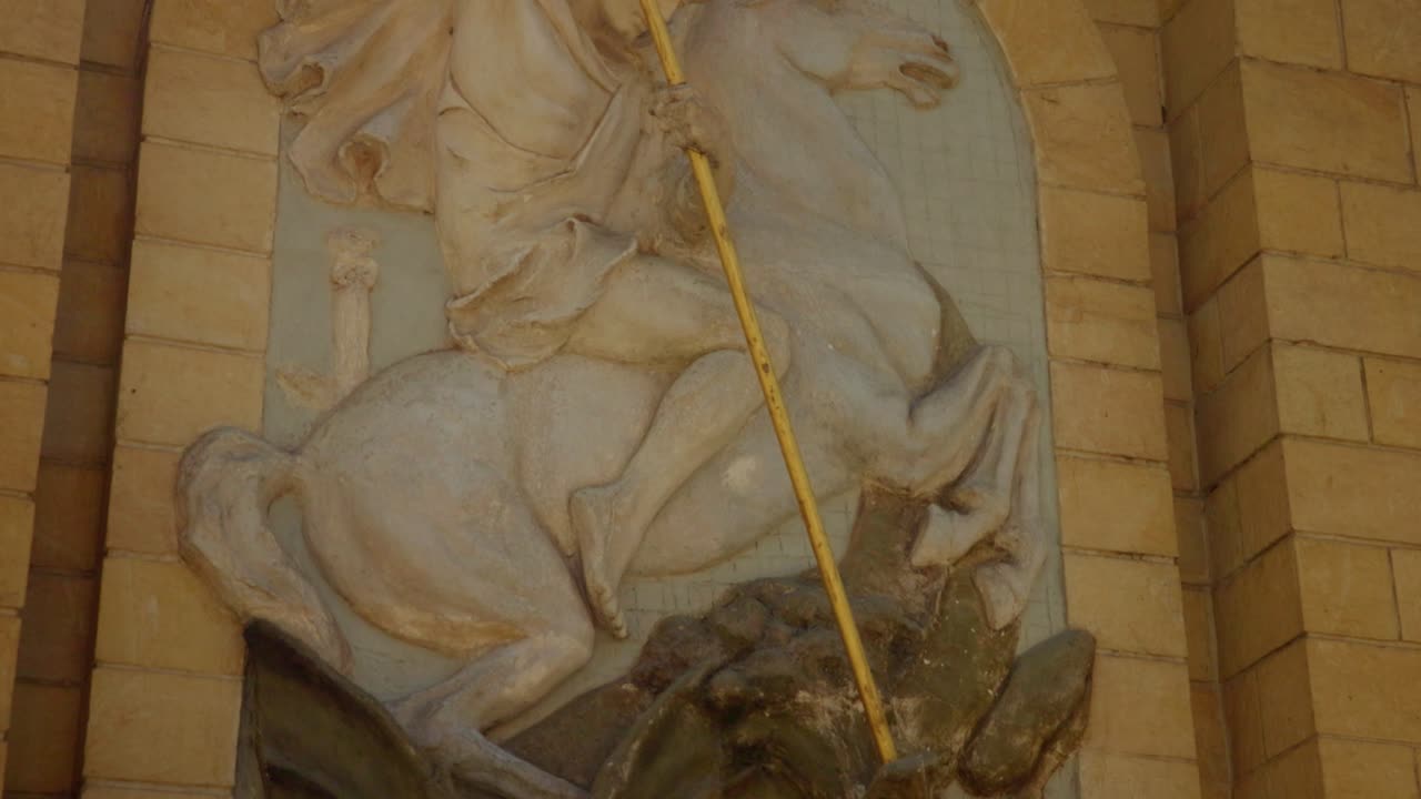 escultura en relieve de la pared de san jorge matando al dragón con una lanza dorada
