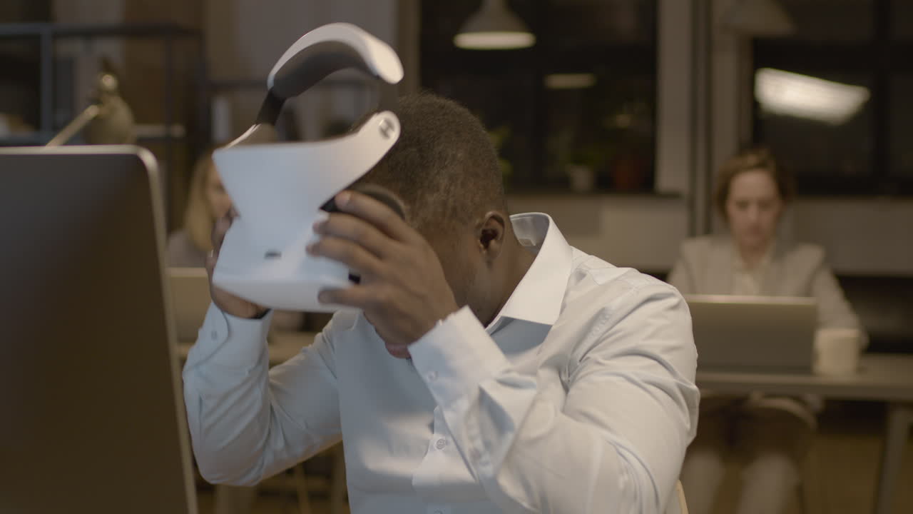 가상 현실 안경을 쓰고 사무실 책상에 앉아 있는 미국 남자의 클로즈업 보기 1