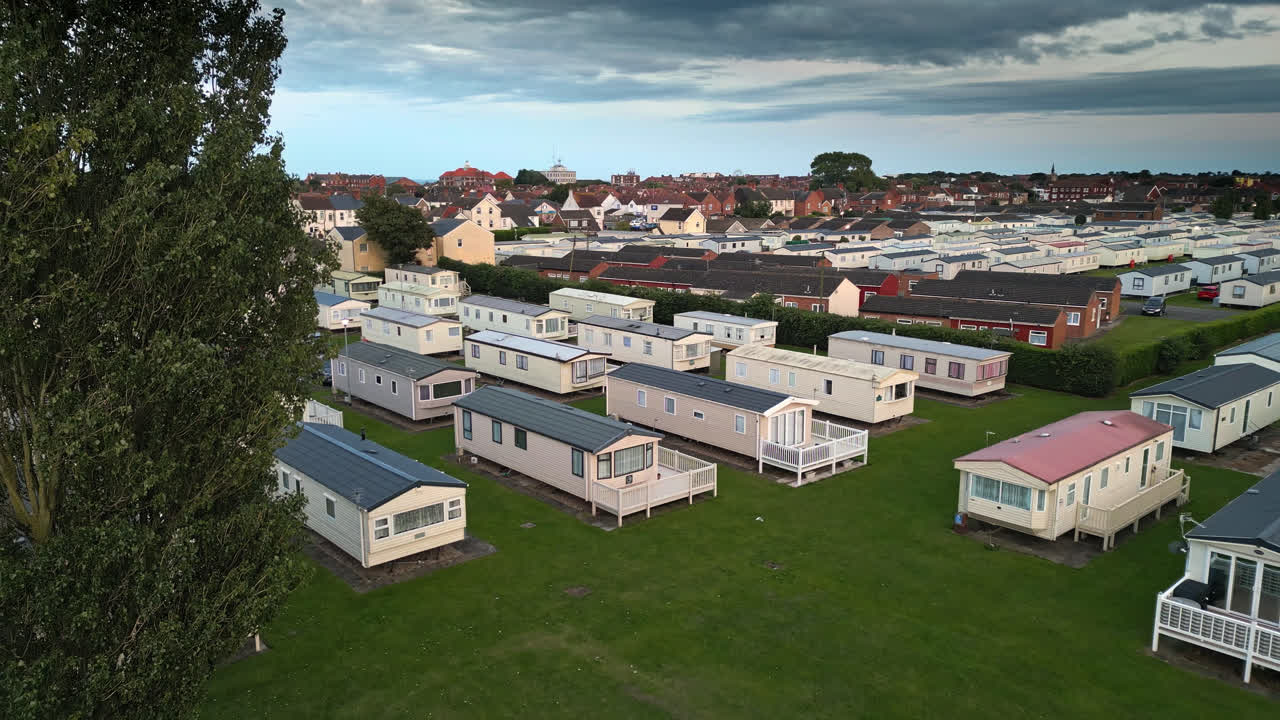 Drone's view of Skegness seaside town during summer sunset, revealing holiday park, beach, sea, and caravans in sweeping views