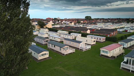 Drone&#039;s view of Skegness seaside town during summer sunset, revealing holiday park, beach, sea, and caravans in sweeping views