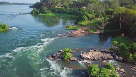 aerial static drone shot of the river nile in uganda, africa, showcasing the river's rapids, rocks, lush vegetation, and the source area of the mighty river