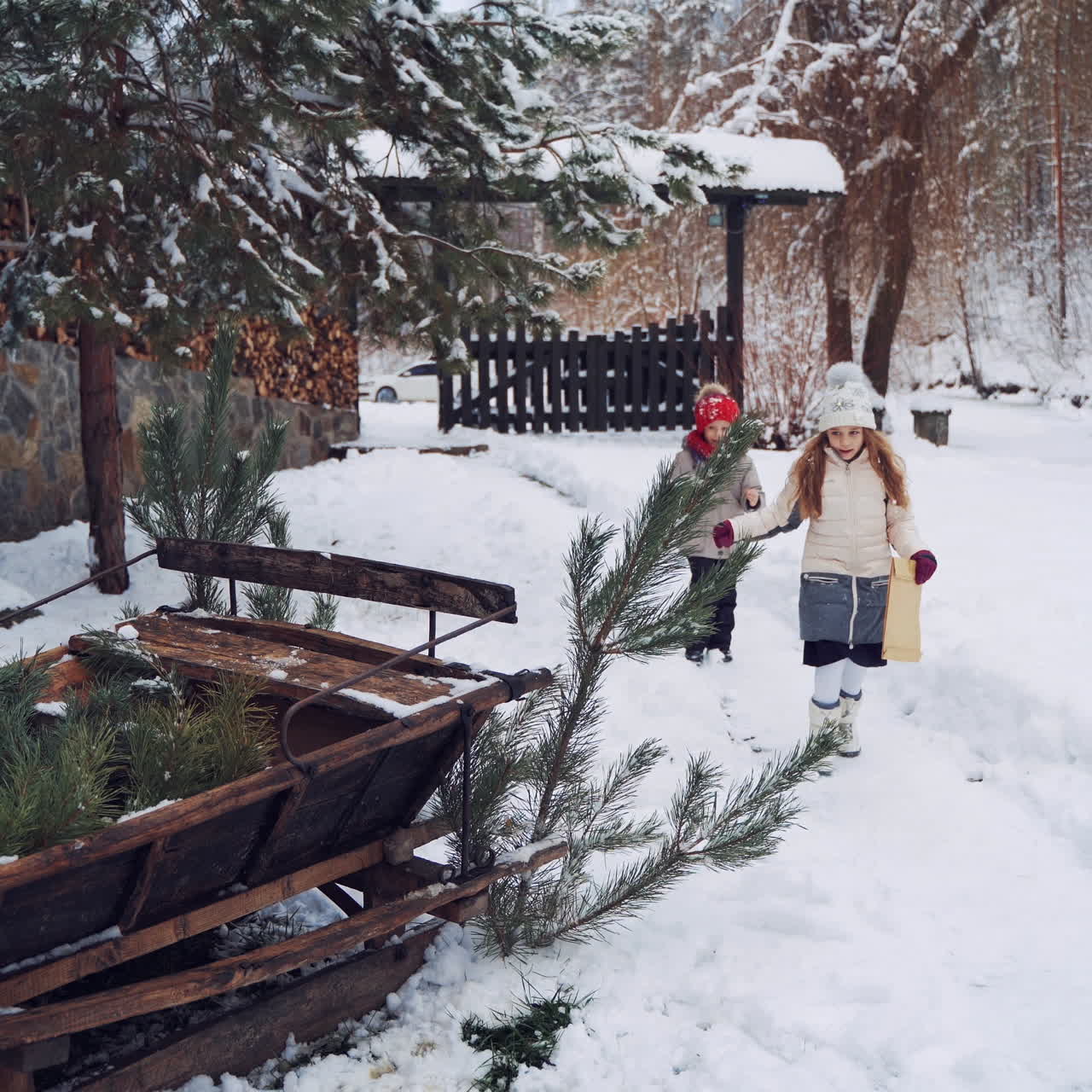 Happy children with envelope in winter in the yard. Two little kids coming to old wooden sledges and brown sheep on the snowy background.