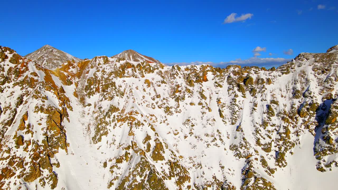 Cime montuose rocciose coperte da un sottile strato di neve in una bella giornata. Ripresa panoramica con drone.