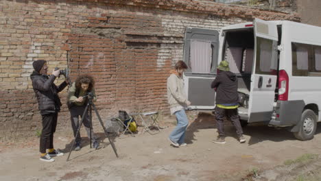 dos compañeros de producción instalando una cámara en la calle y otros dos trabajadores sacando material para una grabación desde una furgoneta 1