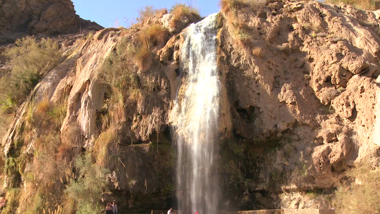 la gente fa il bagno sotto una grande cascata di acqua calda in una località del mar morto in giordania